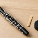 Student clarinet with a reed and cork grease on a wooden table