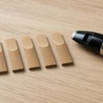 Clarinet reeds in a row next to a clarinet mouthpiece with ligature